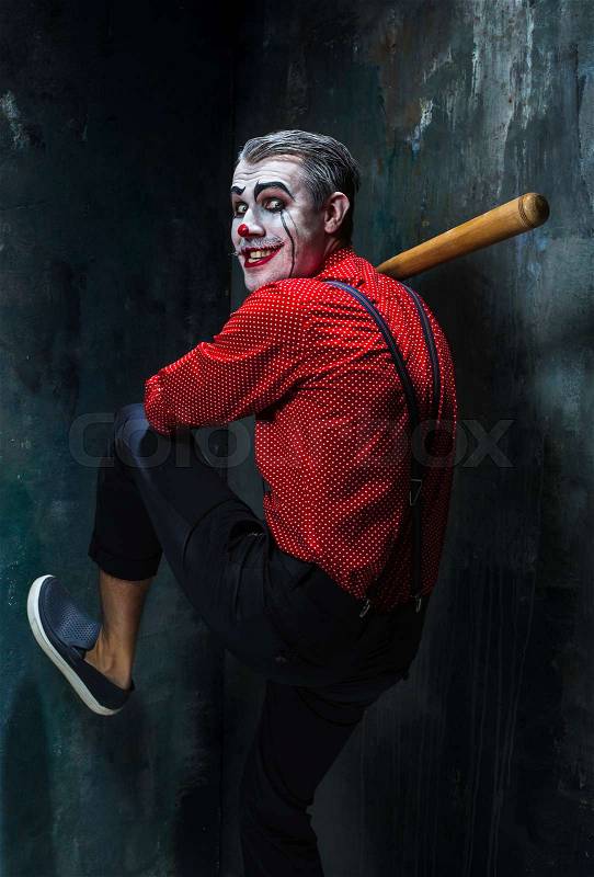 The scary clown and baseball-bat on dack. Halloween concept of horror and murderer, stock photo