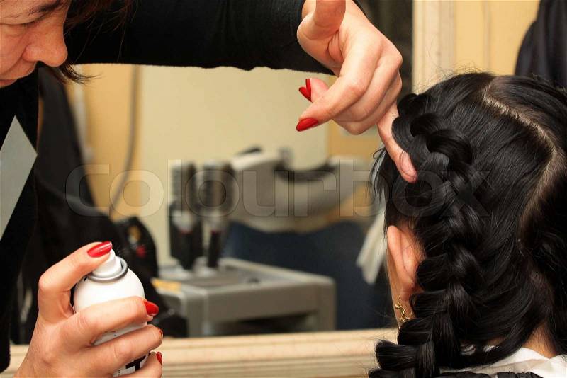 Hairdresser makes hairstyle on the long black hair woman, stock photo