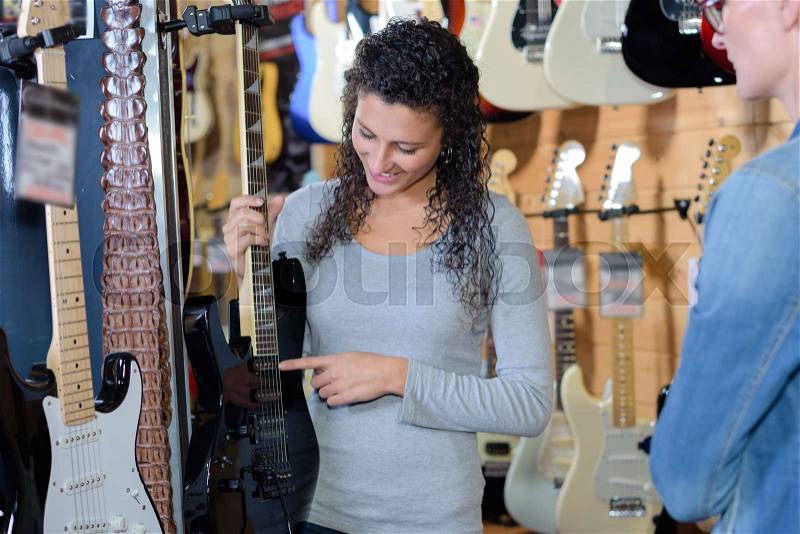 Musician choosing electric guitar in music shop, stock photo