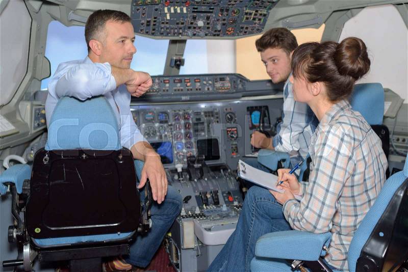 Young people questioning man in cockpit of aircraft, stock photo