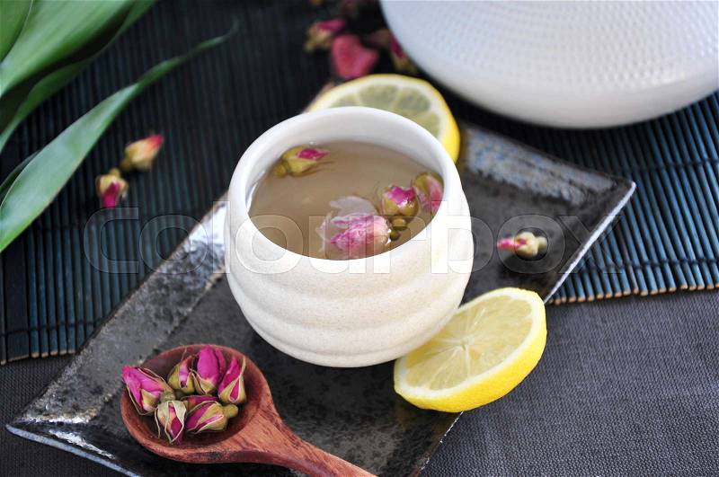 Rose tea cup with spoon of dried roses on tray, stock photo