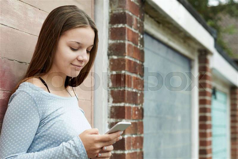 Teenage Girl Texting On Mobile Phone In Urban Setting, stock photo
