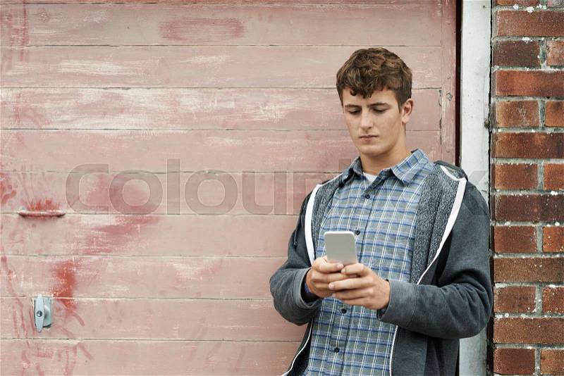 Teenage Boy Texting On Mobile Phone In Urban Setting, stock photo