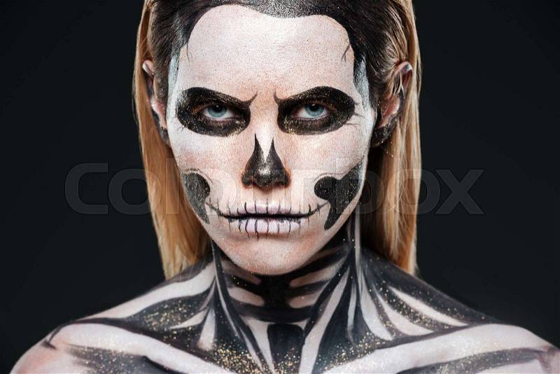 Closeup of young woman with terrifying skeleton makeup over black background, stock photo