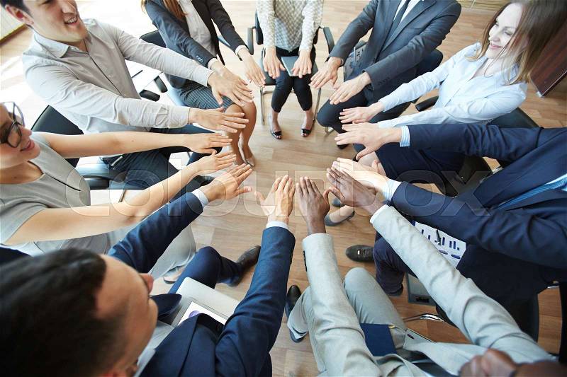 Business colleagues huddling hands at training, stock photo