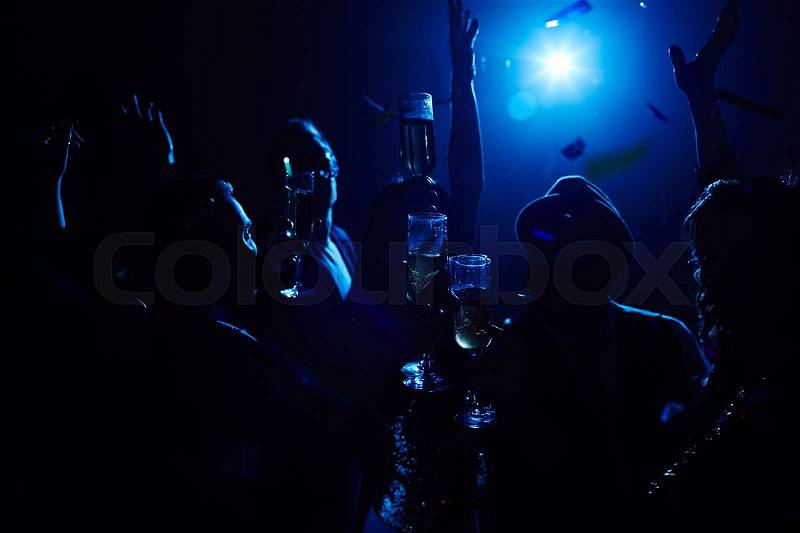 Cheerful people toasting with alcoholic drinks in the darkness, stock photo