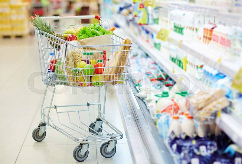 Consumer cart with food products in hypermarket, stock photo