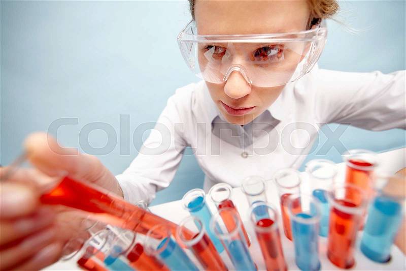 Woman scientist taking out tubing with red liquid, stock photo