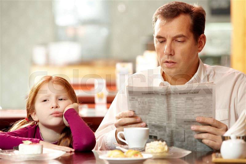Bored girl sitting in café with her father who is reading paper, stock photo