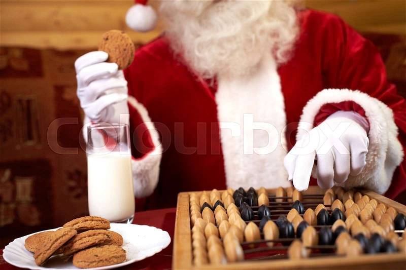 Closeup of abacus and cookies and milk with Santa Claus on background, stock photo