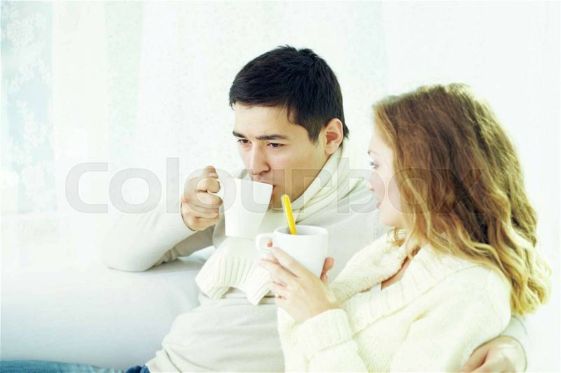 Ill couple sitting at home and drinking medicine, stock photo