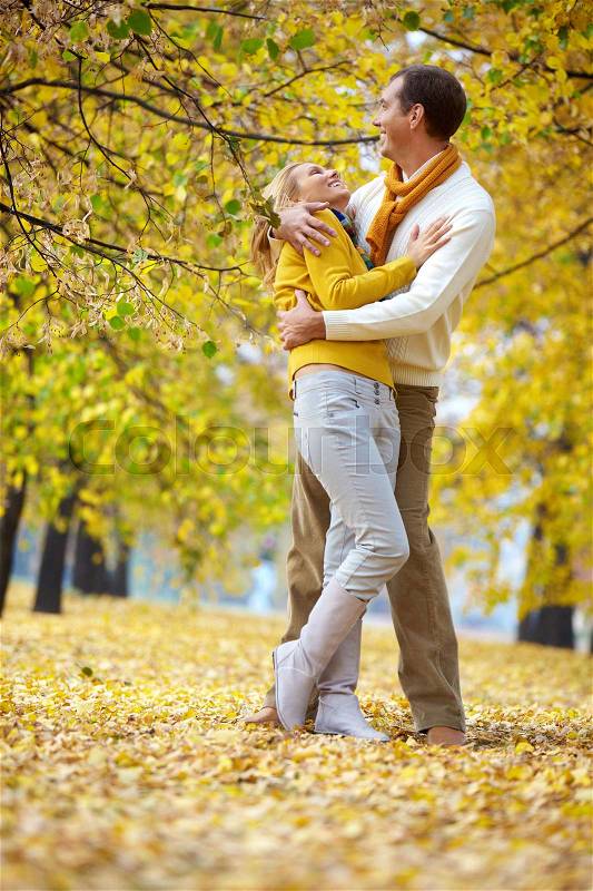 A couple embracing and laughing among autumn trees, stock photo