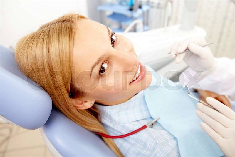 A young woman sitting in dentist chair, looking at camera and smiling, stock photo