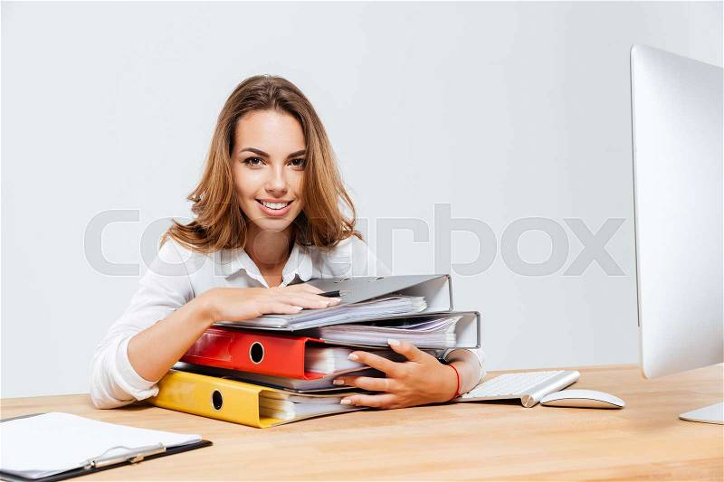 Close up of a happy businesswoman holding folders while sitting at the office desk isoltaed on the white background, stock photo