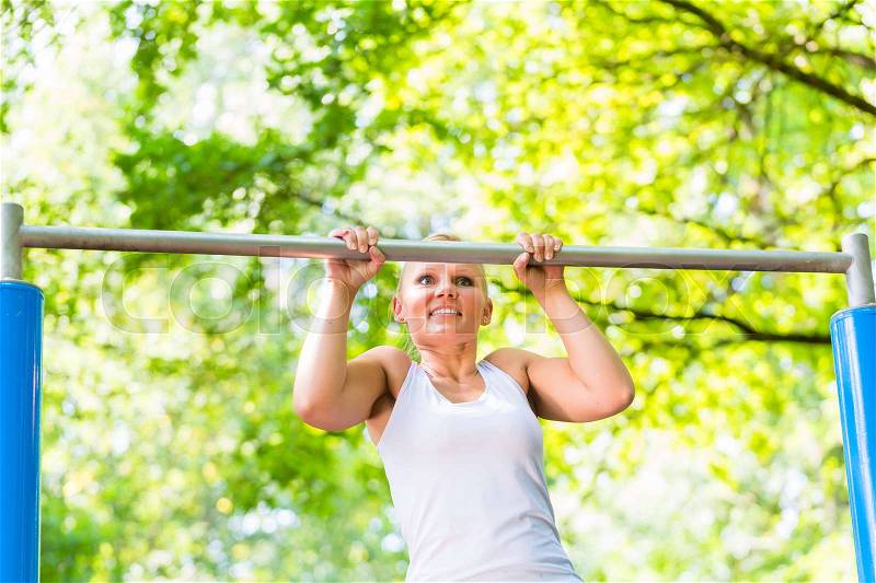 Woman exercising at high bar for better outdoor fitness, stock photo