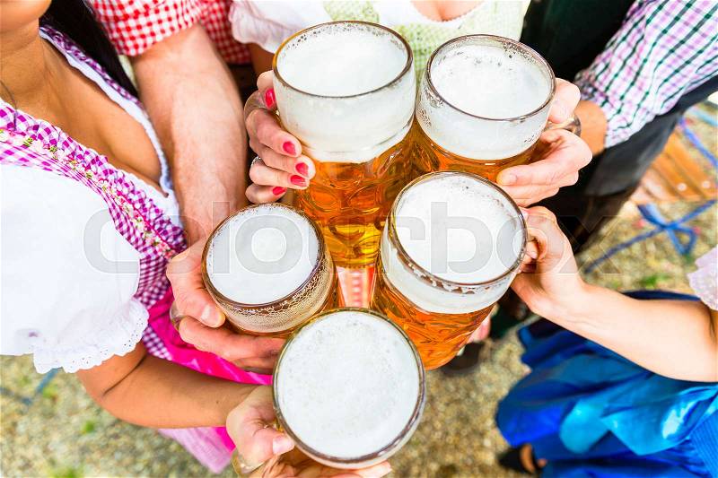 Clinking glasses with beer in Bavarian beer garden, close-up on five beer glasses, stock photo