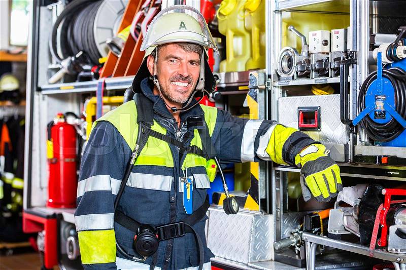 Fire fighter in uniform leaning at vehicle of fire department, stock photo