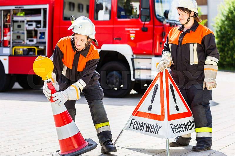 Female fire fighters in emergency operation setting up attention sign, stock photo
