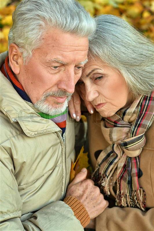 Portrait of a sad senior couple in autumn park, stock photo