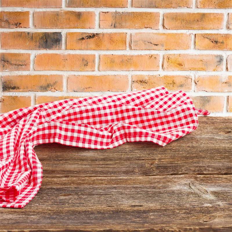 Wooden table with with cloth napkin red brick kitchen wall, stock photo