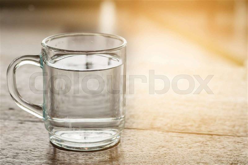 Glass of water on a wooden floor in the coffee shop with the morning light, stock photo