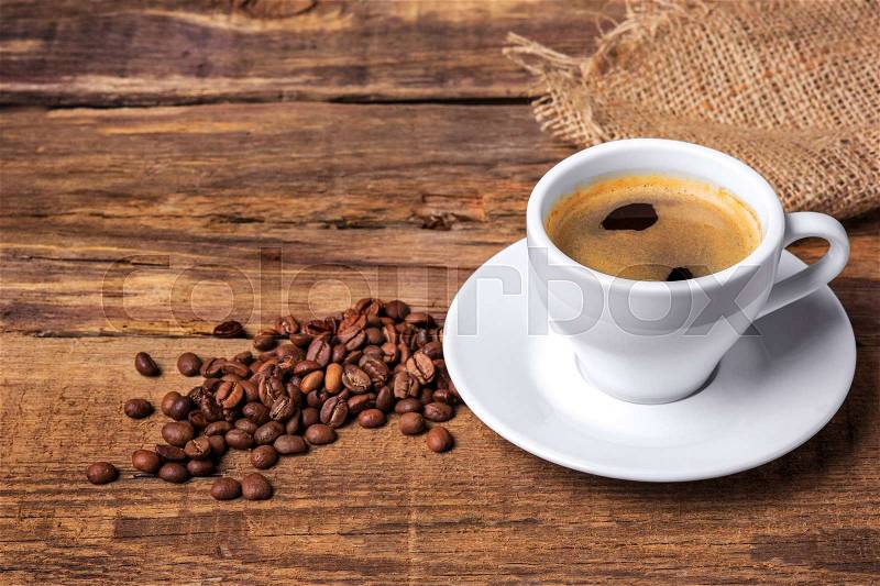 Coffee cup and beans on a wooden table. Dark background, stock photo