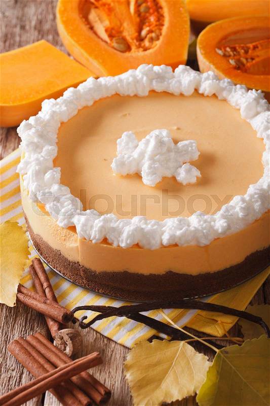 Pumpkin cheesecake with cinnamon, vanilla and whipped cream close-up on the table. Vertical\, stock photo
