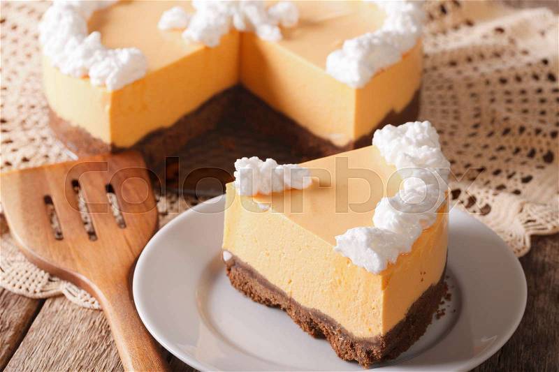 A piece of pumpkin cheesecake with whipped cream close-up on a plate on the table. horizontal , stock photo