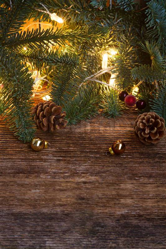 Christmas border with fir tree and glowing lights on old wooden background, stock photo