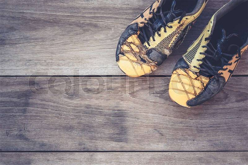 Old football shoes on grey wooden plank background, stock photo