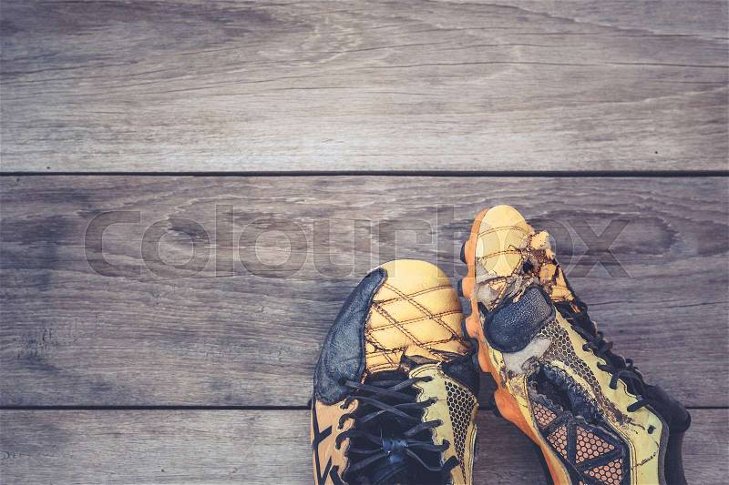 Old football shoes on grey wooden plank background, stock photo