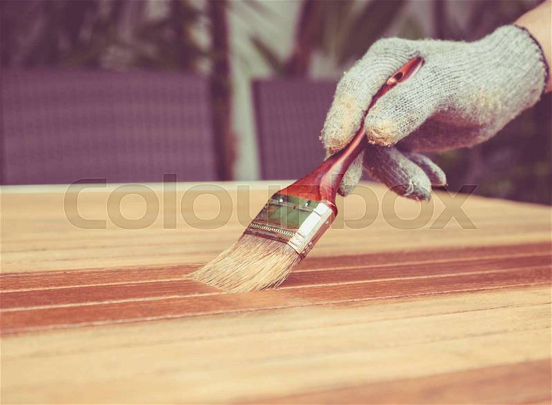 Close up paintbrush in hand and painting on the wooden table. Retro and vintage style, stock photo