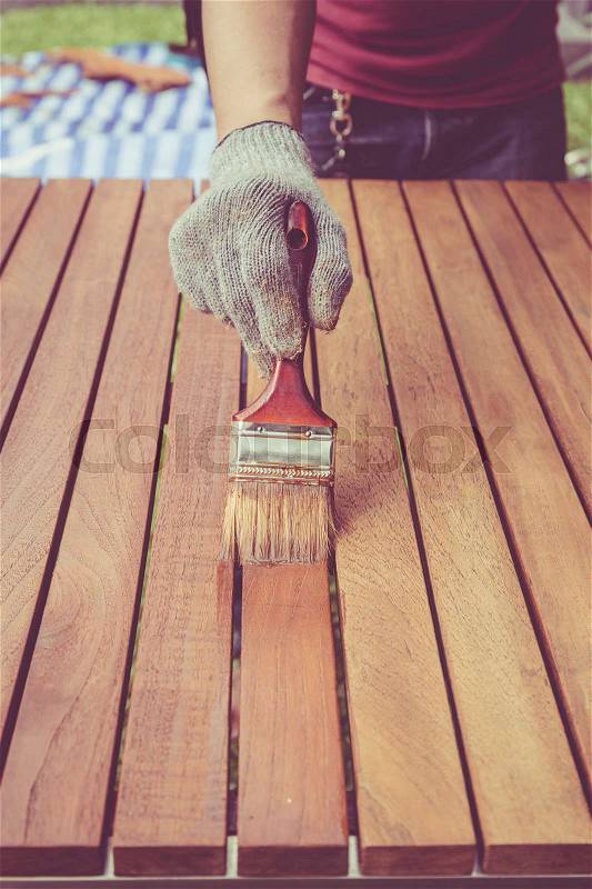 Close up paintbrush in hand and painting on the wooden table. Retro and vintage style, stock photo