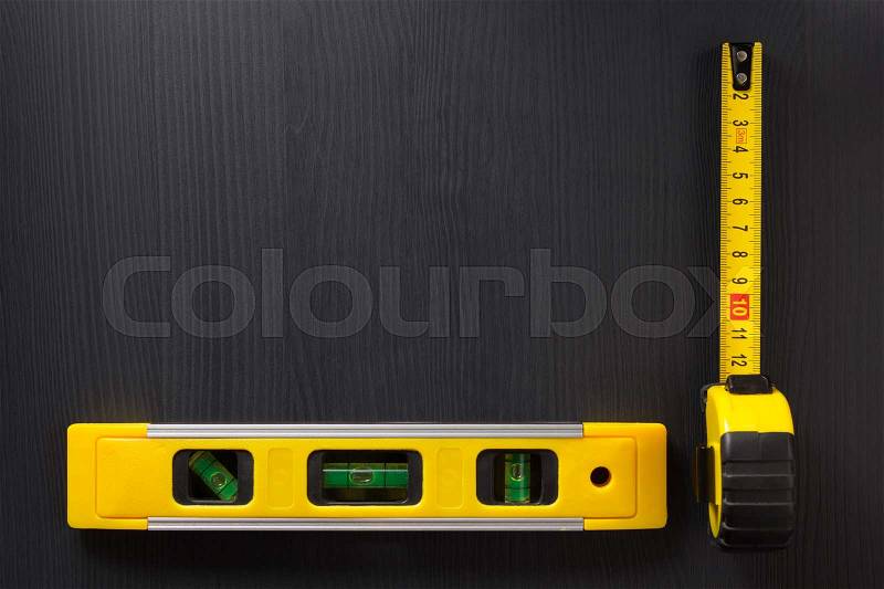 Tape measure and level on wooden texture, stock photo
