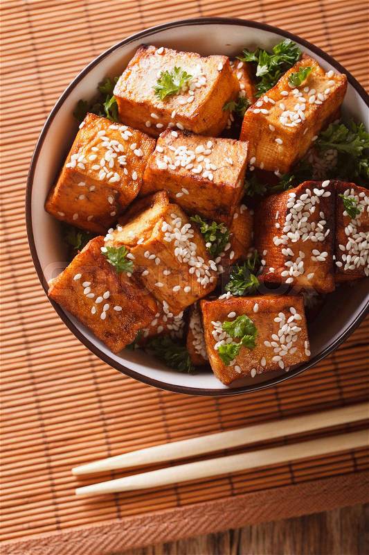 Stir fry tofu with sesame seeds and herbs in a bowl close-up. vertical view from above\, stock photo