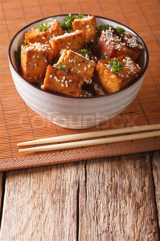 Stir Fry dish: tofu cheese with sesame seeds and garlic in a bowl close-up on the table. vertical\, stock photo