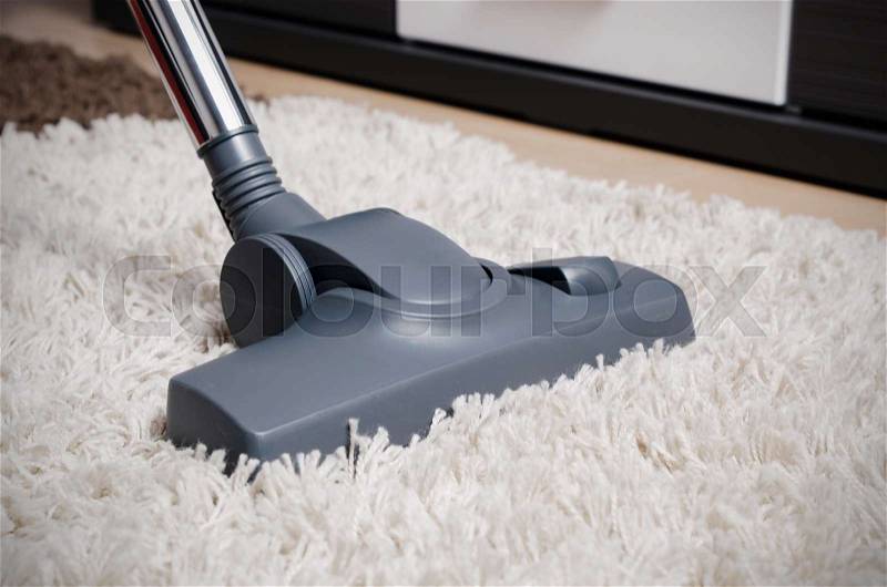 Vacuum cleaner cleans the white shaggy carpet. Close up view, stock photo