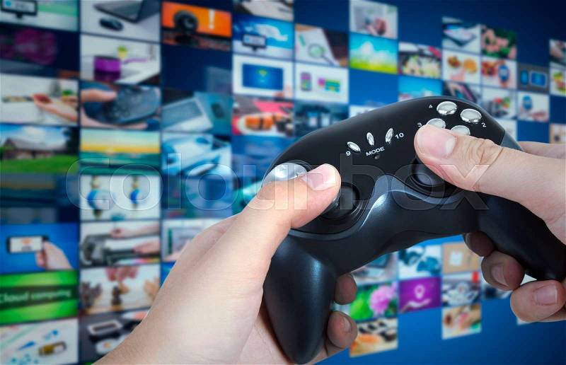 Gamer holding game pad in hands. Game play controller with streaming multimedia in background concept, stock photo