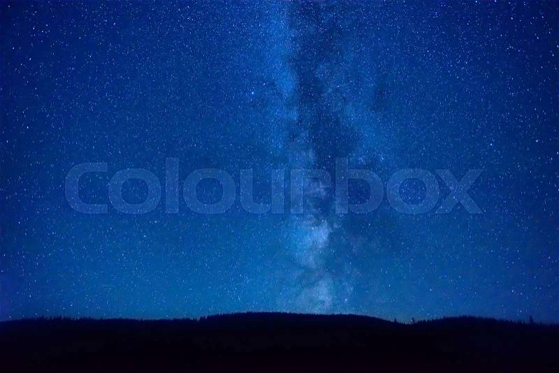 Night dark blue sky with many stars and milky way galaxy above a mountain, stock photo