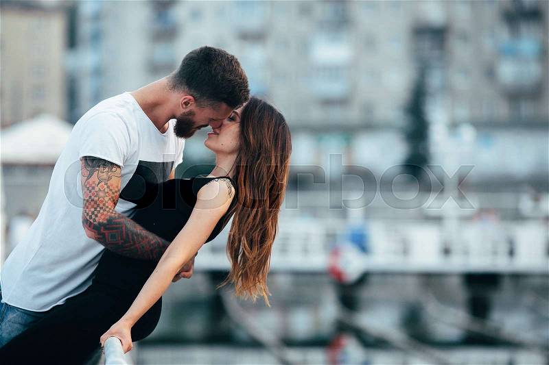 Couple kissing against the backdrop of the city by the lake, stock photo