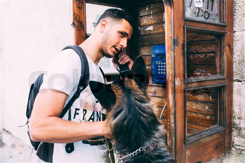 Man and a dog in a phone booth, posing at the camera, stock photo