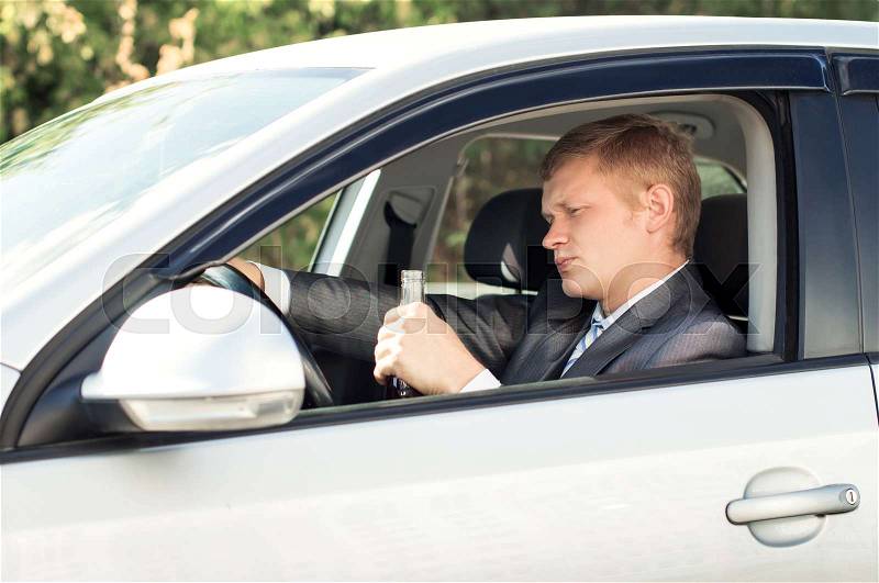 Drunk driver sits behind the wheel of a car, stock photo
