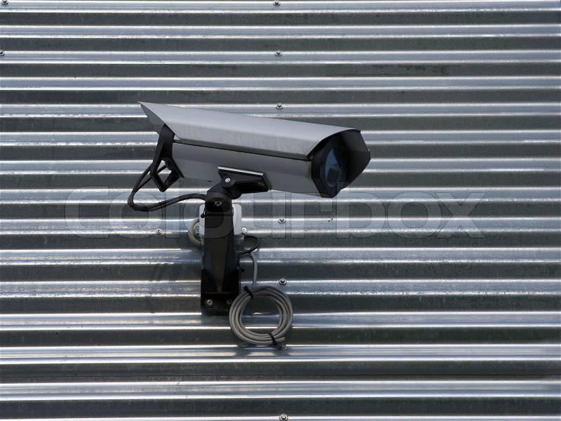 Surveillance video camera attached on a wall of a building, stock photo