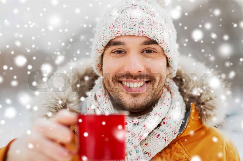 People, season, drinks and leisure concept - happy man with tea cup outdoors in winter, stock photo
