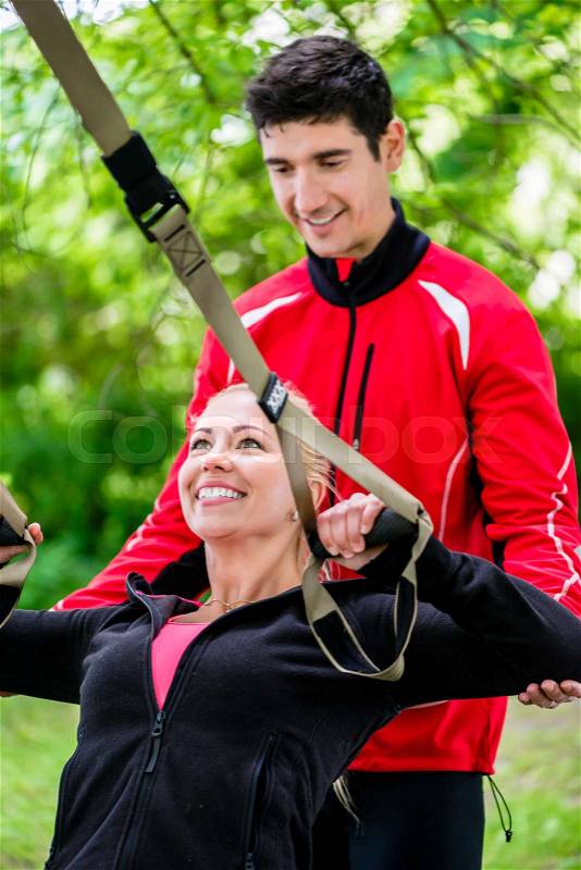 Sport woman with trainer at sling training, stock photo