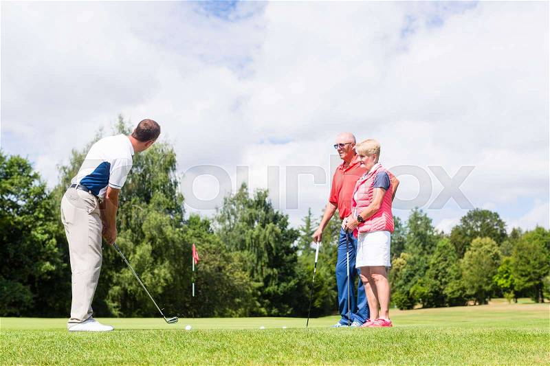 Golf pro practicing the sport with senior woman and man , stock photo