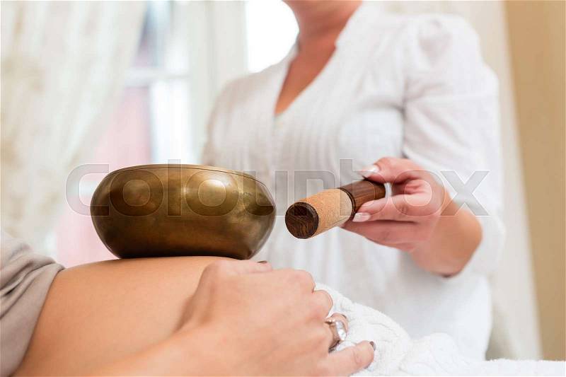 Pregnant woman getting sound bowl wellness treatment, stock photo