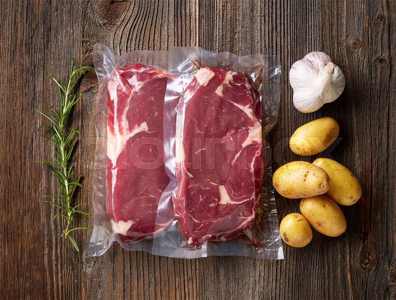 Fresh beef steak for sous vide cooking on wooden table, stock photo
