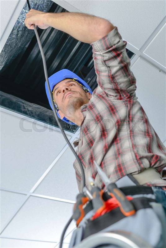 Electrician repairing wiring in an office, stock photo