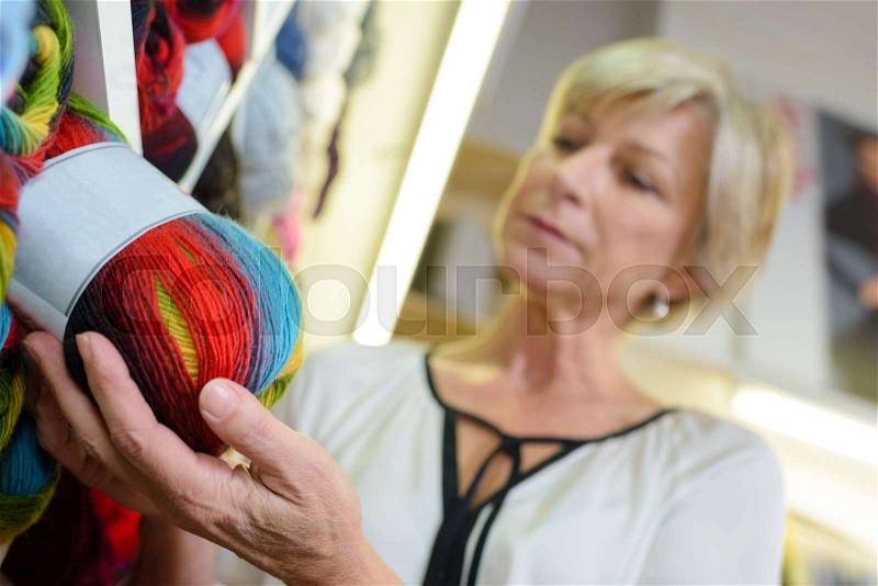 Woman choosing ball of wool, stock photo